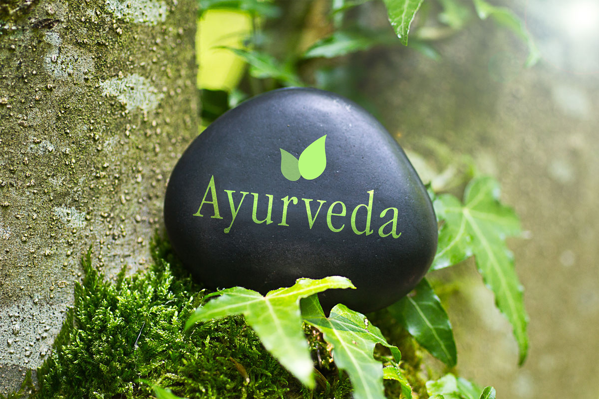 ayurveda text written on a black rock with nature green background.